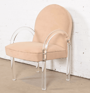 A contemporary armchair with a rounded back and upholstered seat and backrest. The chair features curved armrests and legs constructed from clear acrylic material. The upholstery appears to be a soft, textured fabric. The frame is supported by four cylindrical acrylic legs. — 3D model