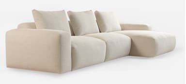 A contemporary, plush, light beige sectional sofa featuring a modular design with clean lines and a low profile. It consists of multiple sections, including a three-seat segment and an extended chaise lounge, all upholstered in a textured fabric. The backrests are composed of loose, rectangular cushions, complementing the soft, rounded appearance of the base and arms. — 3D model