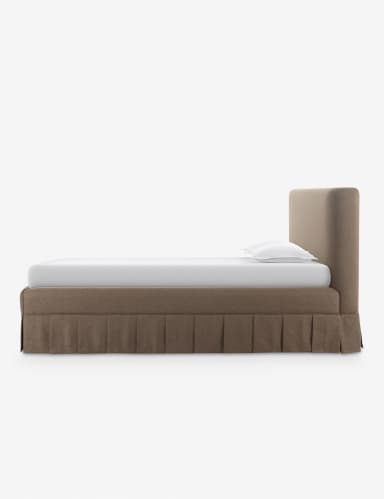 A contemporary upholstered platform bed featuring a soft, rounded headboard and a matching base with an integrated pleated bed skirt. The bed is rendered with a white mattress and two white pillows, suggesting a complete sleep system. The upholstery has a textured, fabric appearance in a neutral brown or taupe color. — 3D model