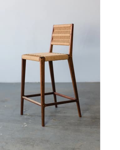 A bar stool with a wooden frame and a woven seat and backrest. The stool features four tapered legs connected by a lower stretcher for stability. The seat and backrest are constructed from a natural woven material, creating a textured surface. The wooden frame appears to be dark-stained. — 3D model