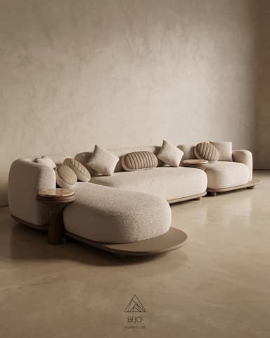 A large, contemporary modular sectional sofa system featuring rounded, organic forms upholstered in a light beige, textured boucle-like fabric. The sofa comprises multiple seating modules, including a chaise lounge component, and incorporates two circular side tables with marble tops and dark wooden bases. The entire seating arrangement rests on a contrasting, flat, light brown or taupe platform base. Several throw pillows are included, with some featuring a distinct ribbed, circular design. — 3D model