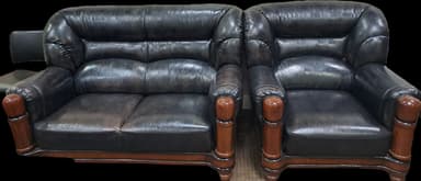 A traditional-style two-seater loveseat upholstered in dark, possibly distressed, leather. It features rolled arms, a button-tufted backrest, and exposed turned wooden legs and frame accents. — 3D model