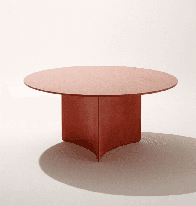 A modern coffee table with a circular top and a pedestal base. The base appears to be constructed from multiple curved panels that meet at the center, creating a sculptural effect. The surface of the table has a slightly textured finish. — 3D model