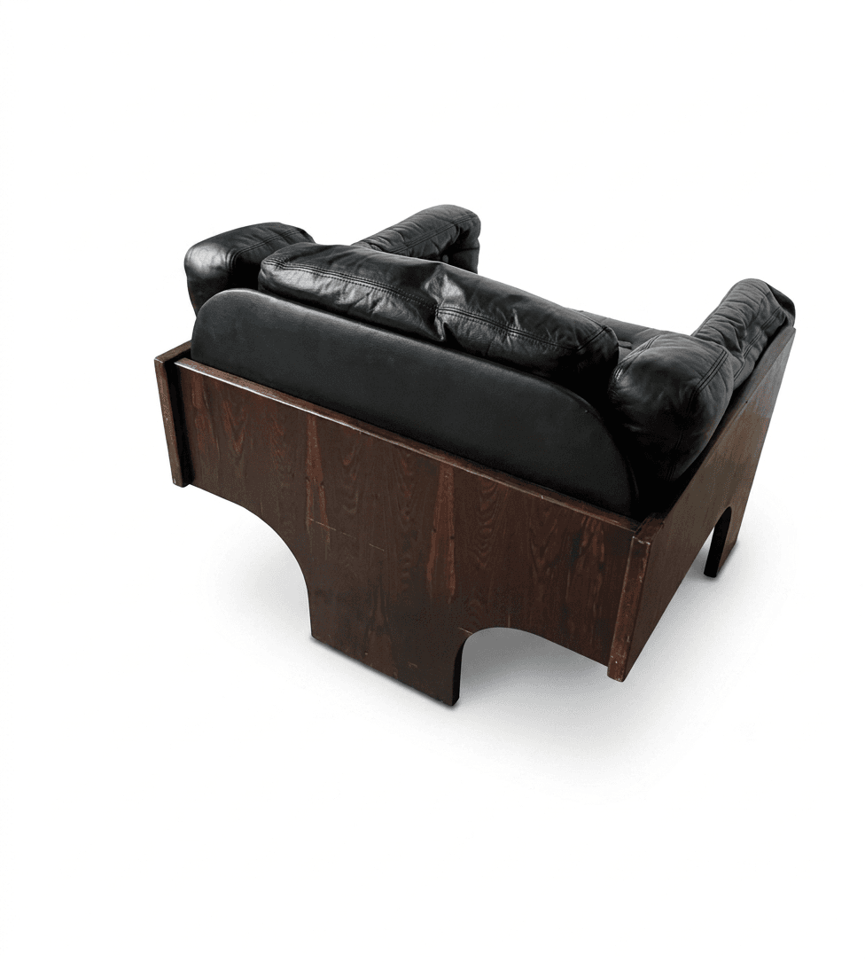 A robust lounge chair featuring a distinctive dark wood veneer frame, likely rosewood, with deep-set black leather cushions. The chair's base forms a solid, geometric structure with cut-out arches, providing a foundational aesthetic. The upholstery consists of plush, padded black leather, including a seat cushion, backrest, and armrests, suggesting a comfortable seating experience. The overall design exhibits characteristics of Mid-Century Modern style with a touch of architectural solidity. — 3D model