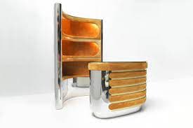 A modern, uniquely designed bar with a wooden countertop and a chrome base. The countertop is finished in a warm wood tone and features a series of horizontal slats for a textured effect. The backsplash is made of a similar wood and features three shelves with a curved edge, creating a sleek and stylish design. The chrome base has a smooth and reflective surface, contrasting with the wood. The overall design of the bar is minimalist and modern, showcasing a blend of natural materials and sleek metal finishes. — 3D model
