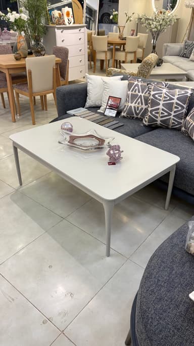 A modern rectangular coffee table featuring a light grey or off-white tabletop with softly rounded corners, supported by four subtly tapered legs matching the tabletop's color and finish. — 3D model