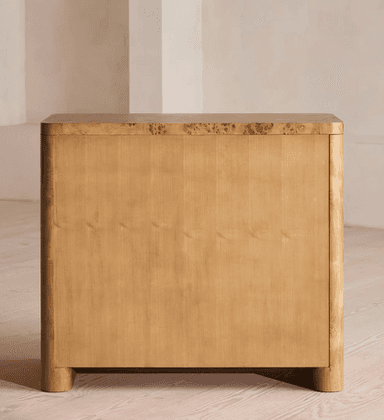 A three-drawer chest of drawers crafted with burl wood veneer, featuring rounded corners and edges, and circular recessed brass pull handles. The unit stands on integrated rounded feet. — 3D model