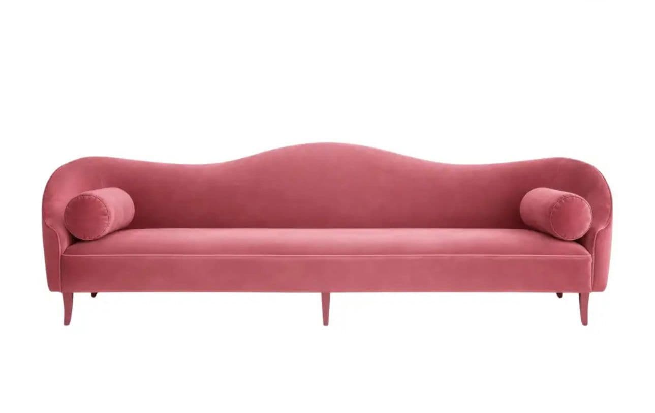 A pink velvet chaise lounge with a curved silhouette, featuring a low back that flows into an armrest on one side and a rounded bolster pillow at each end. It is supported by four slender, angled legs. — 3D model