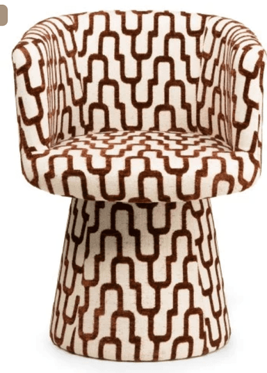 A modern armchair with a rounded, upholstered form. The chair features a high back that curves into armrests, enclosing the seating area. The base is a tapered pedestal, also upholstered, providing stability. The upholstery displays a geometric pattern of interlocking U-shapes in brown on an off-white background. — 3D model
