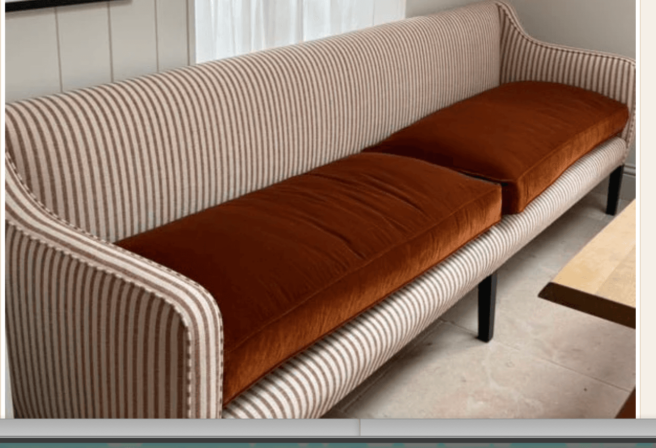 A two-seater upholstered settee featuring a high back, slightly flared arms, and four dark, tapered legs. The frame is covered in a striped fabric, complemented by solid reddish-brown seat cushions, and finished with decorative nailhead trim. — 3D model