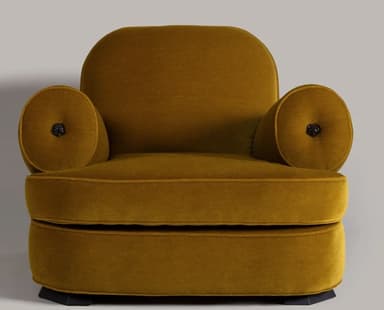 A compact, rounded armchair upholstered in a mustard-yellow velvet fabric. The armchair features a high, curved backrest that seamlessly transitions into padded armrests. The seat is low and broad, with a plain upholstered base. The overall design is plush and inviting, with a visible seam line indicating the upholstery construction. — 3D model