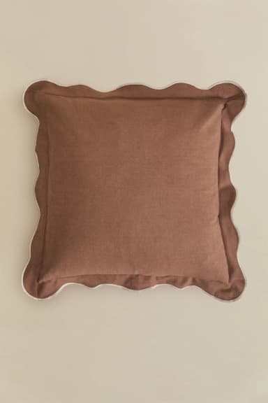 A square-shaped throw pillow featuring a solid brown (or terracotta) color. The pillow is distinguished by its scalloped edge, which is finished with a thin, lighter contrasting piping, adding a decorative flair. The fabric appears to be a soft, matte textile, possibly linen or cotton. — 3D model