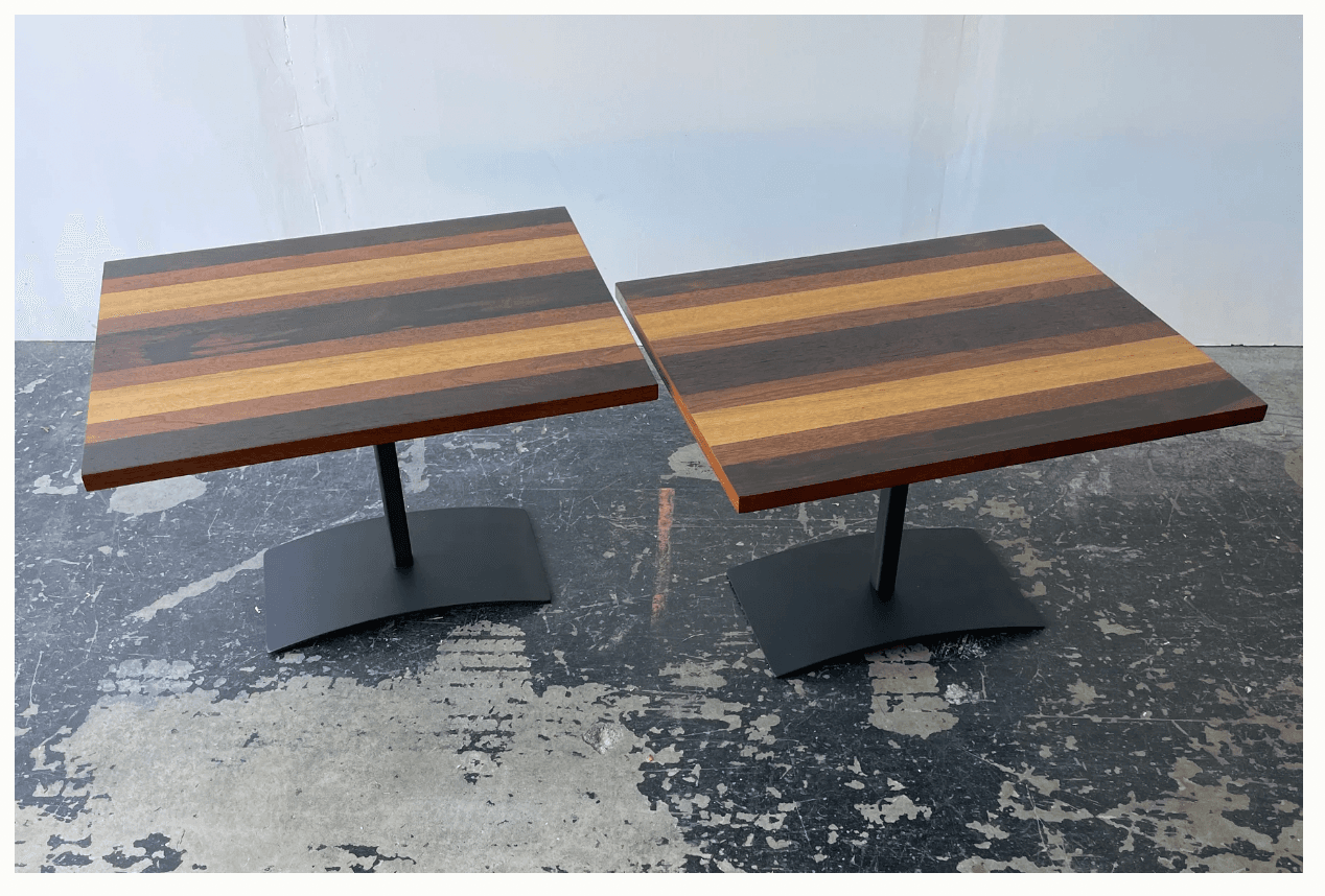 A square dining table with a top composed of alternating dark and light wood planks, supported by a single, centrally located pedestal base with a curved, flat bottom. — 3D model