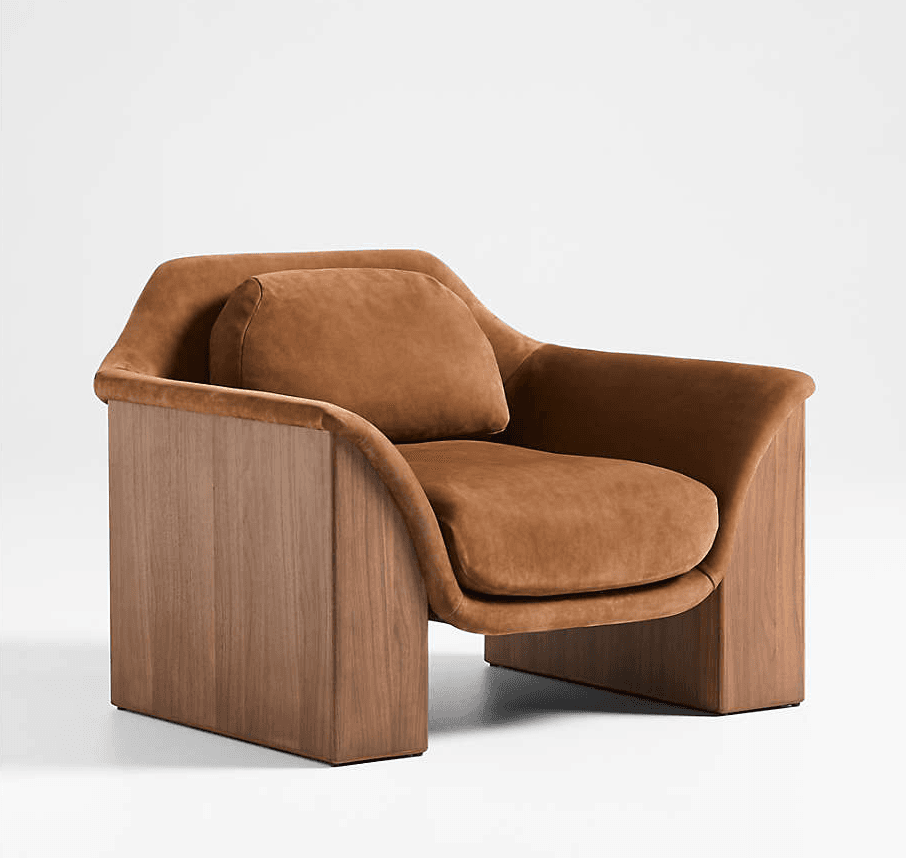 A modern lounge chair featuring a distinctive design with solid walnut wood side panels and plush brown velvet upholstery. The seat and backrest are generously cushioned, appearing to float within the rigid wooden frame. The upholstery follows a smooth, curved form, creating integrated armrests and a comfortable seating experience. A separate, rounded lumbar pillow adds to the comfort and design. The chair has a substantial, sculptural presence with clean lines and warm, earthy tones. — 3D model
