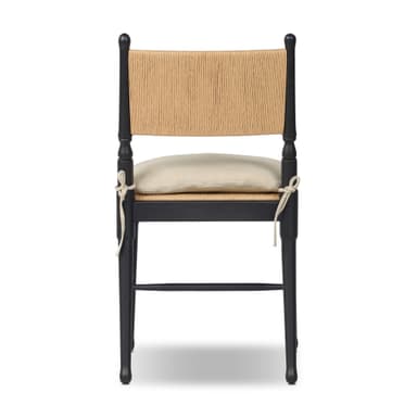 A contemporary dining chair featuring a solid black wooden frame, a natural woven rattan backrest, and a light beige fabric cushion positioned on a cane seat. The chair incorporates turned elements on its back posts and subtly tapered legs. — 3D model