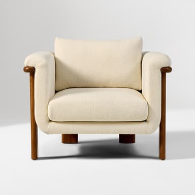 A contemporary armchair featuring a solid wood frame with natural wood grain visible. The seating and backrest are upholstered in a textured, light-colored fabric. The design incorporates a rounded aesthetic with distinct block-style wooden legs and integrated armrests that extend from the frame. — 3D model