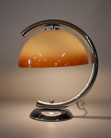 A contemporary table lamp featuring a polished chrome arc frame supporting a frosted amber glass dome shade. — 3D model