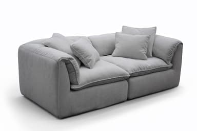 A contemporary, light gray two-seater sofa featuring a plush and inviting design. It consists of two main upholstered sections, providing generous seating. The sofa has thick, soft cushions for both the seat and back, along with several matching throw pillows, all upholstered in a uniform light gray fabric with subtle piping detail. The armrests are wide and softly padded, integrated into the overall plush aesthetic. The piece appears designed for maximum comfort and relaxation, with a low profile and a substantial, inviting presence. — 3D model
