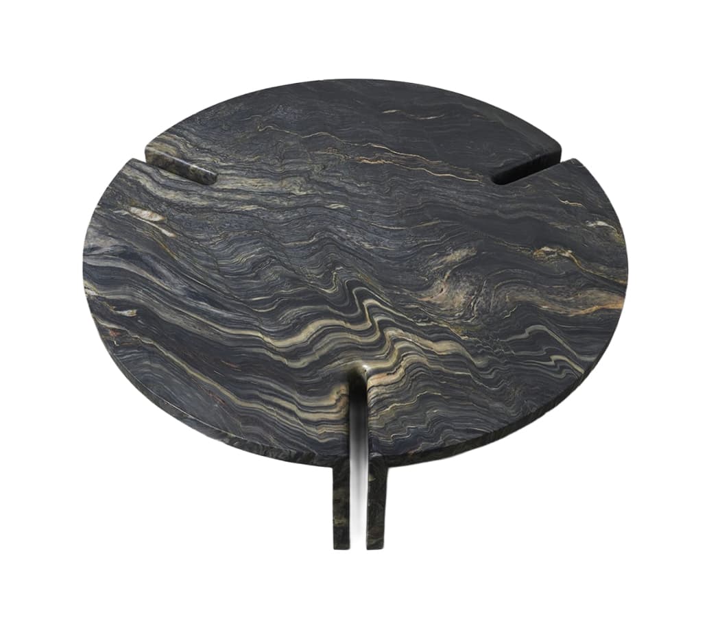 A circular side table crafted entirely from a richly veined dark stone, featuring intricate patterns of black, grey, gold, and brown. The tabletop has three radial cutouts, one of which extends downwards to form an integrated two-legged base structure, giving the piece a monolithic and sculptural appearance. — 3D model