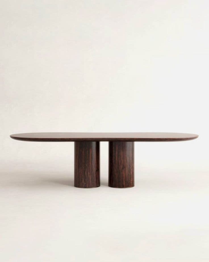 An oval dining table with a dark wood finish, supported by two cylindrical legs positioned centrally under the tabletop. The legs have a prominent grain pattern. — 3D model