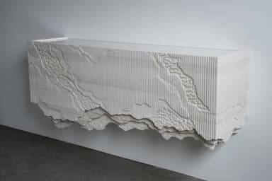 An elongated, rectangular console cabinet featuring a highly textured and sculptural facade and underside, finished entirely in matte white. The top surface is smooth, contrasting with the three-dimensional, relief-carved front and bottom edges that evoke natural rock formations or stratified landscapes. — 3D model