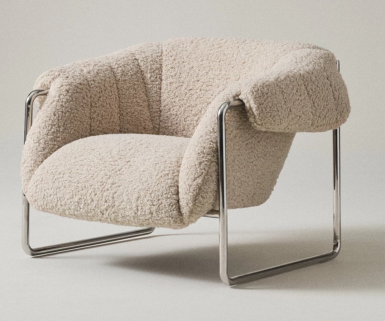 A contemporary lounge chair featuring a sturdy tubular chrome frame and plush, cream-colored boucle upholstery. The chair design incorporates generous padding that appears to rest within the minimalist metal structure, providing a comfortable and inviting aesthetic. — 3D model