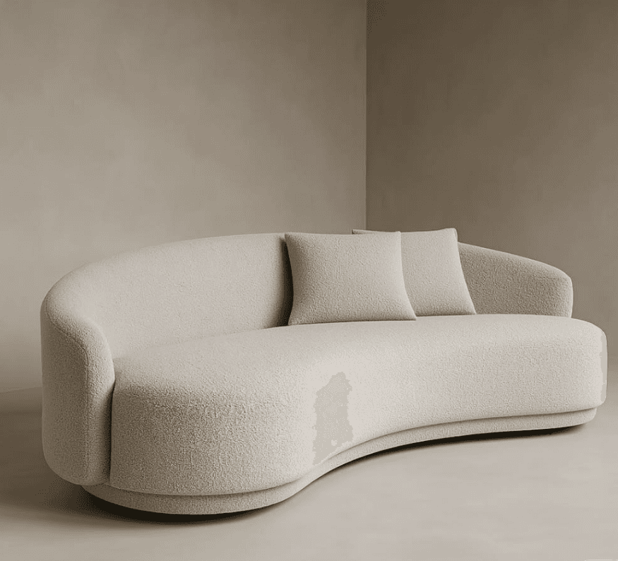 A modern, light beige boucle sofa featuring a distinctive curved or serpentine silhouette, with a continuous low-profile backrest that seamlessly integrates into arms. It has a plush, textured appearance and rests on a subtly recessed base, accompanied by two matching throw pillows. — 3D model