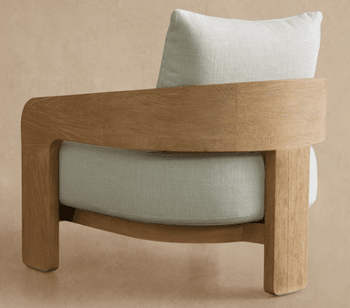 A modern upholstered armchair featuring a light-toned wooden frame and thick, cream-colored fabric cushions. The frame exhibits a prominent natural wood grain texture and gently curved armrests. — 3D model