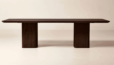 A rectangular dining table crafted from dark wood, featuring a thick, smooth tabletop. The table is supported by two substantial, vertically fluted pedestal bases, providing a modern and minimalist aesthetic. The dark finish enhances its elegant and robust presence. The ends of the tabletop show a subtle rounding. — 3D model
