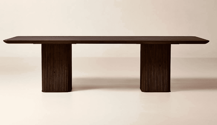 A rectangular dining table crafted from dark wood, featuring a thick, smooth tabletop. The table is supported by two substantial, vertically fluted pedestal bases, providing a modern and minimalist aesthetic. The dark finish enhances its elegant and robust presence. The ends of the tabletop show a subtle rounding. — 3D model