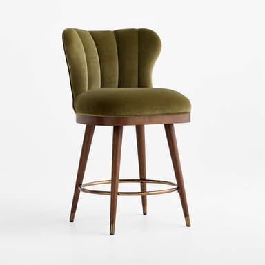 A stylish bar stool featuring an olive green velvet upholstered seat and a distinctive scalloped, channel-tufted backrest. It stands on four angled wooden legs, connected by a circular brass footrest, and finished with brass ferrules on the feet. The design blends luxurious materials with mid-century modern influences. — 3D model