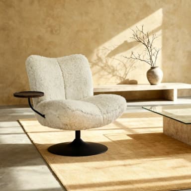 A plush, cream-colored armchair with a distinctive, textured upholstery that resembles sheepskin or faux fur. The chair features a low-profile, rounded silhouette with segmented cushions for the seat and back. It is mounted on a black, circular swivel base. A small, dark wooden circular side table is attached to the left side of the chair via a black metal arm. — 3D model