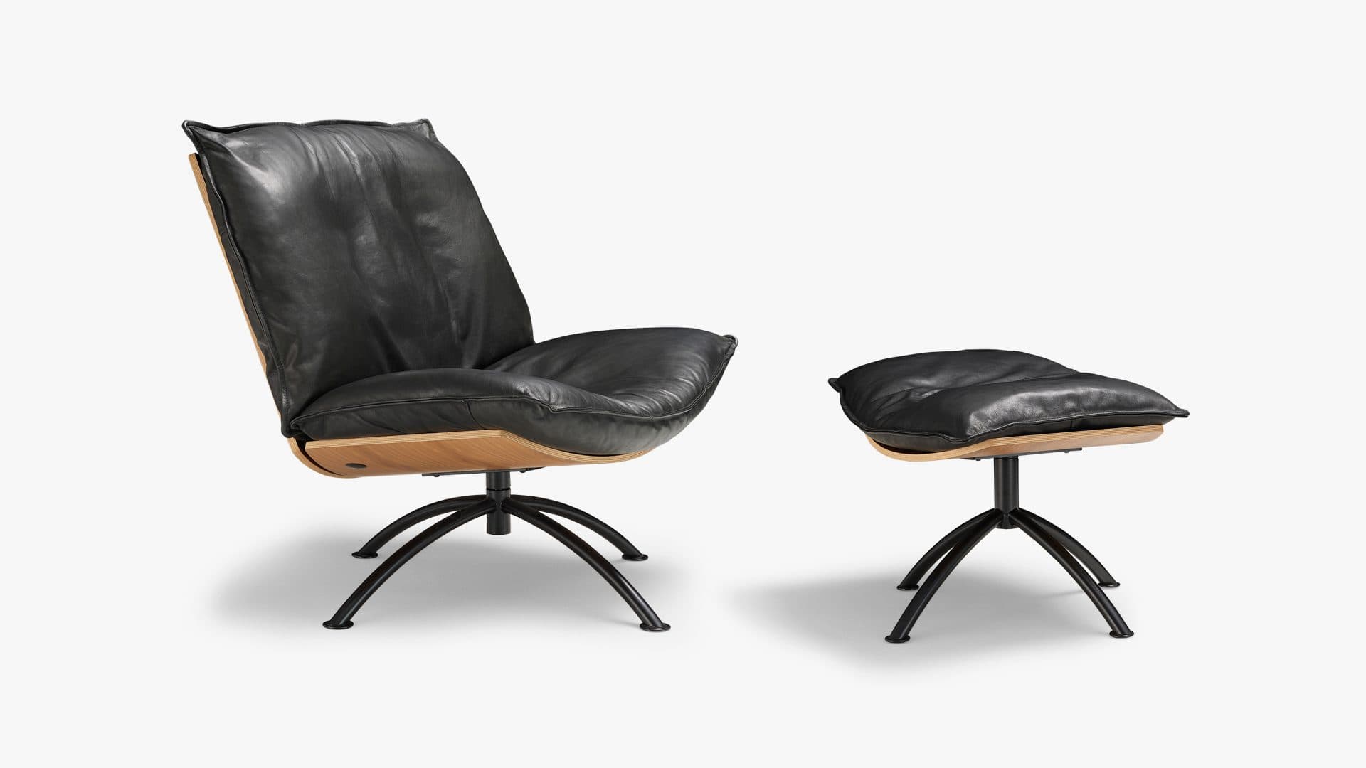 A modern lounge chair and matching ottoman featuring black leather upholstery, molded plywood shells, and black metal swivel bases with splayed legs. — 3D model