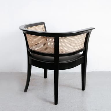 An elegant armchair featuring a black wooden frame with a curved backrest and natural cane webbing. The seat appears to be upholstered in a dark material, likely black leather or fabric. The chair has a classic yet versatile design. — 3D model