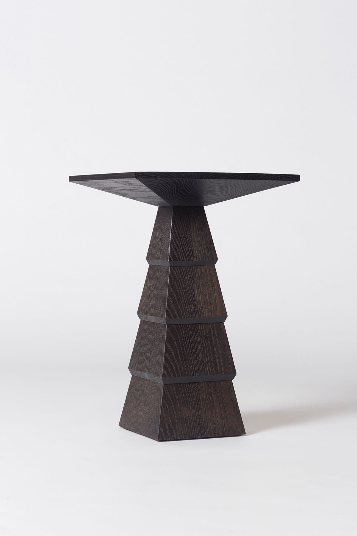 A contemporary dark stained wood pedestal table featuring a distinctive geometric base composed of stacked, tapering pyramid-like sections. The tabletop is a flat, square surface with visible wood grain. — 3D model