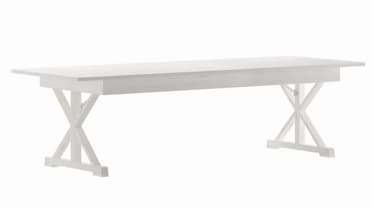 A long, rectangular dining table finished in matte white, featuring a sturdy tabletop and two distinct trestle bases. Each base is constructed with X-shaped supports connected by a central horizontal beam at the top, and rests on two parallel feet. The design is simple, robust, and evokes a modern farmhouse or rustic aesthetic. — 3D model