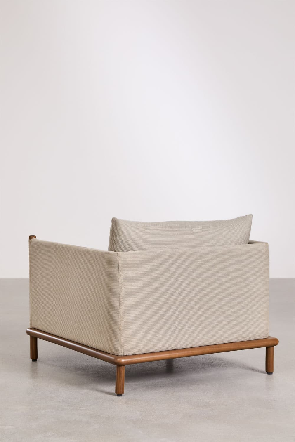 A modern lounge chair featuring a plush, upholstered body in a light beige/grey fabric set upon an exposed, warm-toned wooden base. The chair has a boxy, minimalist design with integrated, low armrests and a loose, rectangular back cushion. The slender, cylindrical wooden legs are slightly splayed, providing stability and contributing to the chair's contemporary aesthetic. — 3D model