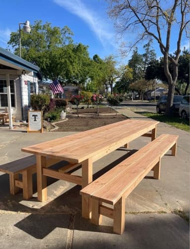 A natural wood picnic table accompanied by two separate, matching wooden benches, designed for outdoor use. The table and benches feature a slatted construction and robust block legs. — 3D model
