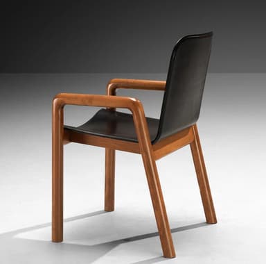 A modern armchair with a dark, possibly leather, seat and backrest, supported by a visible wooden frame. The armrests are integrated into the wooden structure and have a curved, rounded profile. The legs are straight and also made of wood. The overall design appears to be minimalist and functional. — 3D model