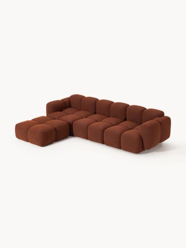 An L-shaped modular sectional sofa composed of individual square and rectangular blocks, upholstered in a rust-colored textured fabric. The design features a low profile and rounded edges on each block, creating a plush, inviting appearance. The sofa is configured with a chaise extension on the left side when viewed from the front. — 3D model
