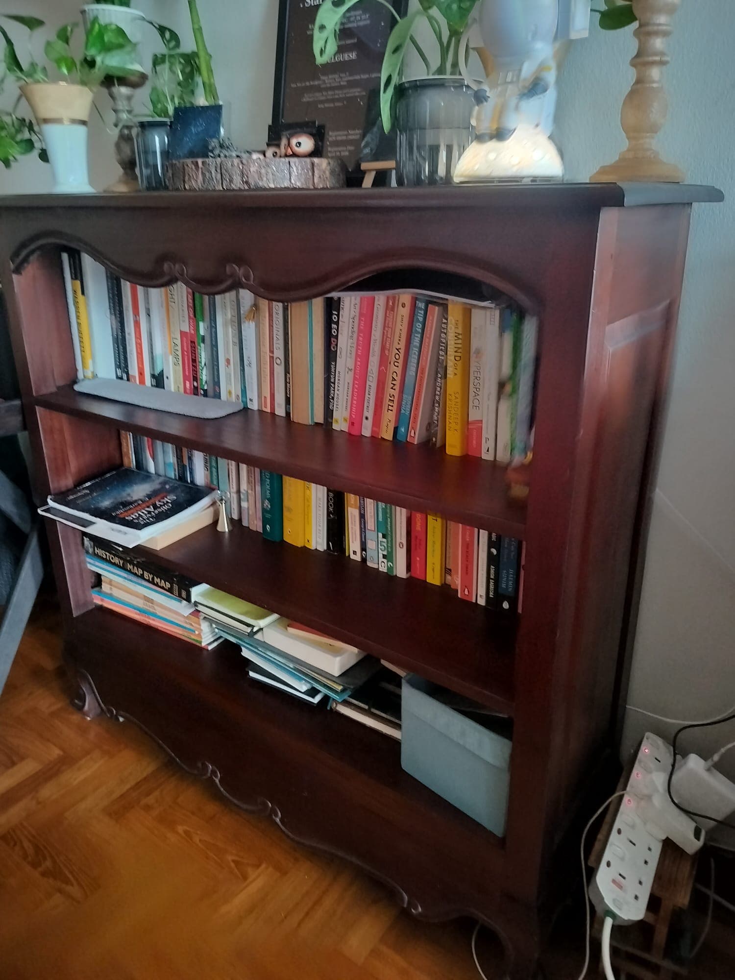 A dark wood open bookcase with three shelves, featuring traditional design elements like scalloped aprons and curved feet, filled with various books. — 3D model