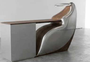 A highly modern and sculptural desk unit featuring an integrated ergonomic chair, a work surface, and a multi-drawer storage cabinet. The design combines a curved, polished metal shell with dark wood accents and a glass side shelf. An illuminated ring fixture is positioned above the chair. — 3D model