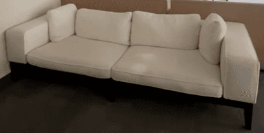 A modern, minimalist sofa featuring white textured fabric upholstery and a distinct exposed black frame. It is designed with two wide square armrests, two large seat cushions, two back cushions, and two smaller accent pillows. The clean lines and contrasting elements give it a contemporary aesthetic. — 3D model
