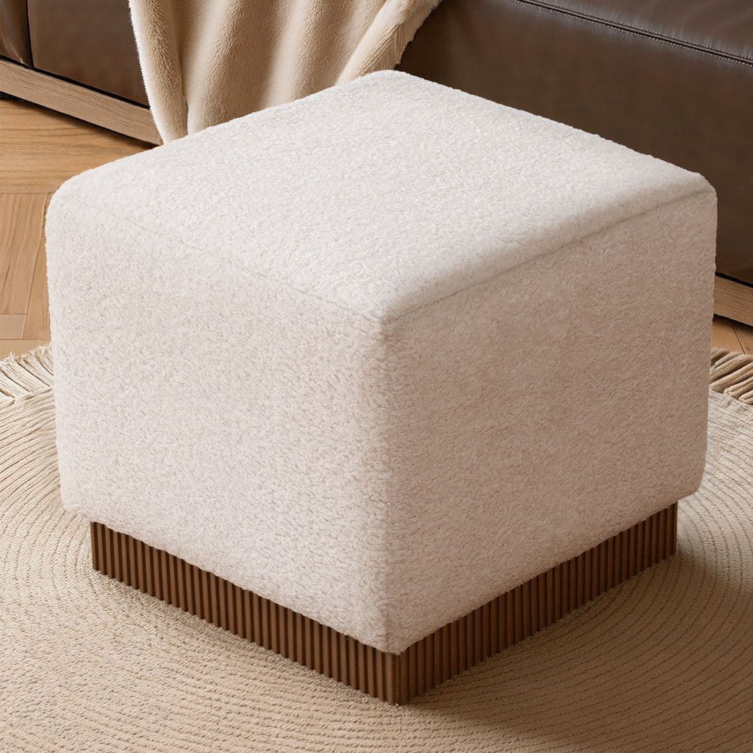 A square upholstered ottoman with gently rounded top edges, covered in an off-white bouclé-textured fabric, and featuring a distinctive fluted dark brown wood base. — 3D model
