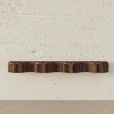 A dark brown wall-mounted console featuring a distinctive wavy front profile with vertical fluting. The unit incorporates three small drawers, each with a subtle pull knob, blending seamlessly into the overall design. The console is made of wood and is affixed to a textured white wall. — 3D model