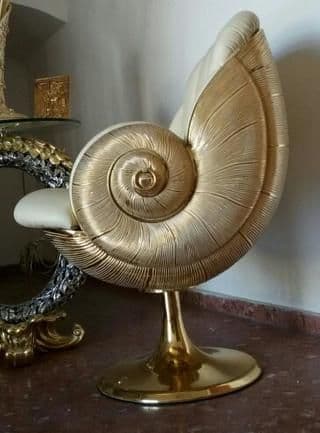 A highly decorative accent chair featuring a distinctive shell-like back and arms in a gold finish, with a cream-colored upholstered seat and backrest, all supported by a matching gold pedestal base. — 3D model
