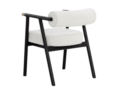 A contemporary armchair featuring a dark, possibly black-stained, wooden frame with clean lines. The seat and cylindrical backrest are upholstered in a light, textured fabric, resembling bouclé or a similar weave. The armrests are an extension of the frame, culminating in subtle brass-finished accents on the outer edges. The chair's design combines minimalist aesthetics with comfortable padding, suitable for various modern interiors. — 3D model