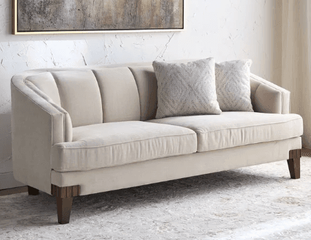 An elegant, cream-colored loveseat featuring an asymmetrical curved back design. The backrest is subtly channel-tufted, providing a structured yet soft appearance. It has two seat cushions and is supported by four dark, tapered wooden legs. Three decorative throw pillows are placed on the seat. — 3D model