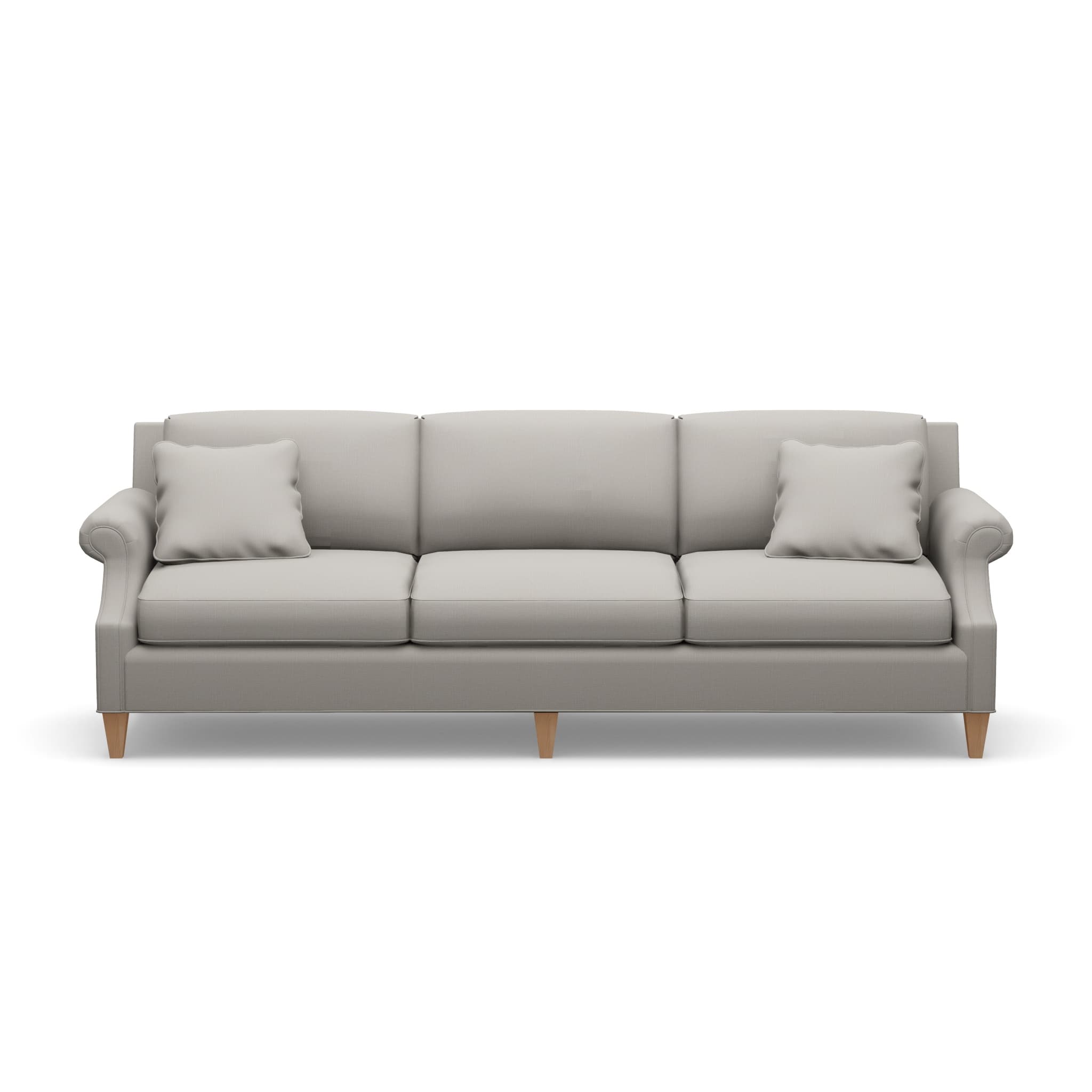 A three-seater sofa with a light gray upholstered body. It features plush seat cushions and back cushions, with a decorative rolled armrest on the left side. Two square throw pillows in a matching light gray fabric are placed on the sofa. The sofa is supported by four short, tapered wooden legs. — 3D model