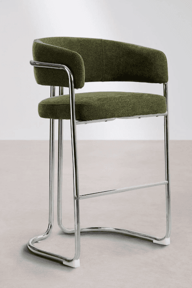 A tall bar stool featuring a bent tubular chrome frame and upholstered seat and backrest. The frame forms a continuous loop creating a sled base and supports the seat and back. The seat and back are cushioned and covered in a textured olive green fabric, with the back curving around to form integrated armrests. A horizontal chrome bar serves as a footrest. The design reflects a modernist aesthetic. — 3D model
